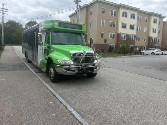 the green incredibly truck minibus signed for “penacook rt 1” pulling toward the curb at the penacook park stop.