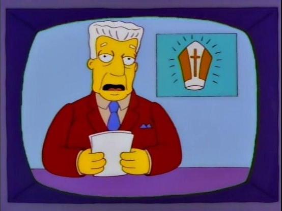 A screenshot of the Simpsons where Kent Brockman is sitting at a news desk, with papers in hand. The chyron behind him displays an illustration of the Pope's hat.
