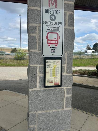the two manchester express bus signs at the concord coach terminal. above is a fairly large sign with the mta logo, route number, and general information, and below is a sign showing the fairly anemic schedule of 7 trips a day.