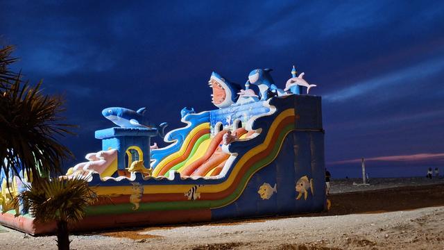 Hüpfburgrutsche mit Hai- und Delfinfiguren am Strand