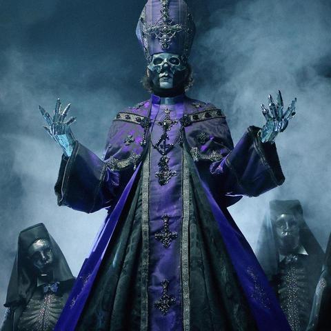 Perpetua V con abito cerimoniale e mitra di colore viola scuro e nero, riccamente decorati con ornamenti e croci rovesciate. Il suo volto è parzialmente coperto da una maschera scheletrica. Dietro di lui si intravedono due Nameless Ghouls con abiti scheletrici e volti parzialmente coperti da una maschera.