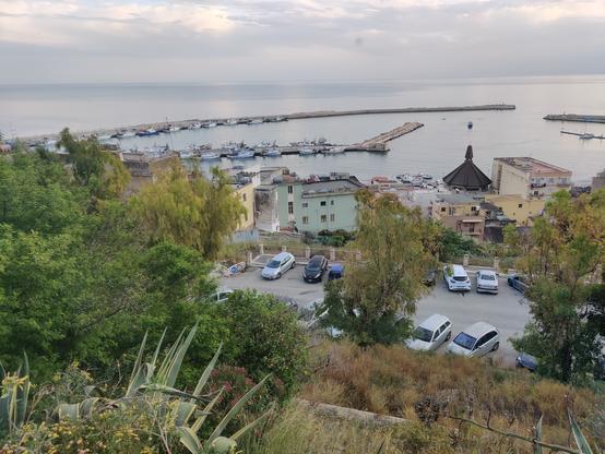 View of an harbour in a sothern Sicilian village.
Slightly from above, houses in mixed state of upkeep, the smal harbour, little boats and the Mediteranian sea.