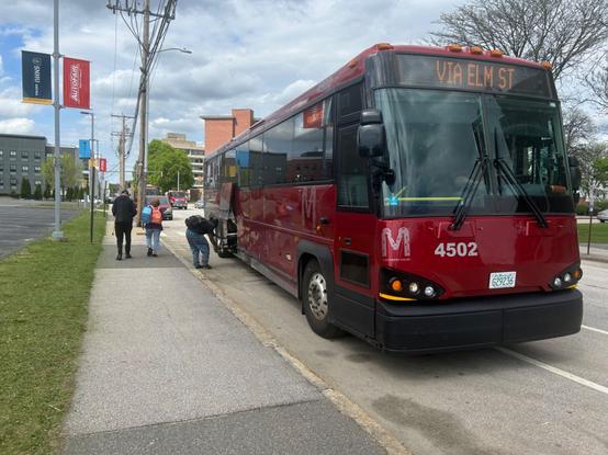 the express bus from concord stopped outside the snhu arena, with someone unloading a bike. it’s signed for the bus garage via elm st