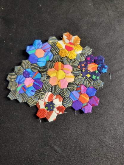 Photograph of the same group of patchwork hexagons all sewn together. Most of them now have a border of the ocean wave fabric.