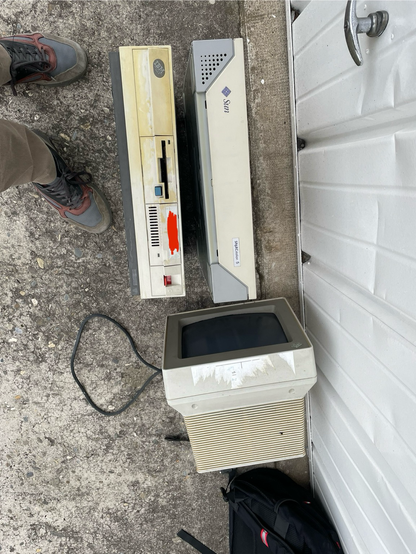 An IBM PS/2 model 30 with a monochrome screen and a Sun SPARCstation 5 on a garage floor.