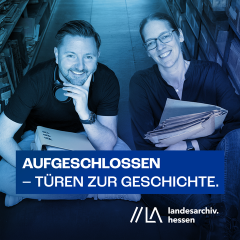 2 Personen sitzen auf dem Boden im Archivmagazin zwischen den Regalen.