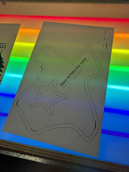 A backwards Texas neon pattern with a star where Arlington is with a rainbow of neon tubes behind it