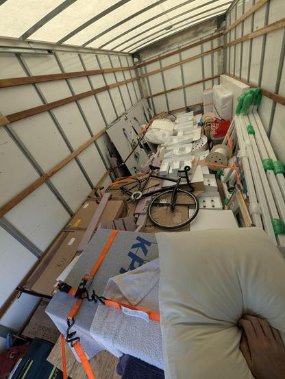 A box truck totally loaded with the Your Magic Is Real sculpture all loaded into it along with a bike, some pillows, suitcases and other boxes and a crate or two