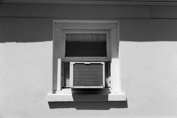 An air conditioner sticking out of a partially lit wall