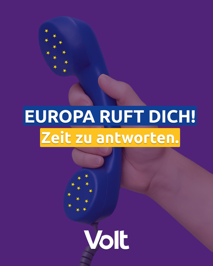 Das Bild zeigt vor violettem Hintergrund eine Hand, die einen altmodischen blauen Telefonhörer (noch mit Schnur) hält. Die Löcher im Hörer und der Sprachmuschel bilden kleine fünfzackige gelbe Sterne.
Darüber steht 
Europa ruft dich! Zeit zu antworten. Volt