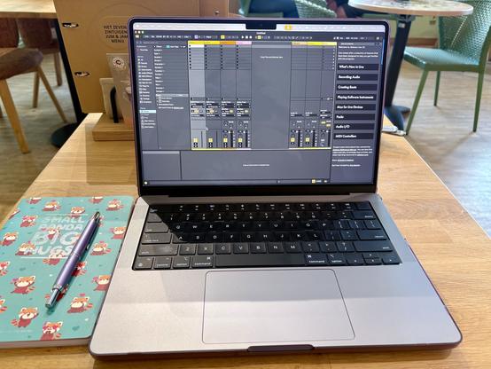 Laptop with ableton live in a cafe. Next is a notebook and a fountain pen.