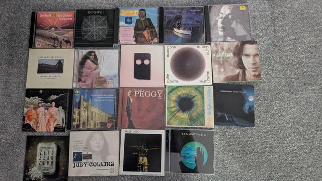 A photo of CDs on a floor with these being by the following :
Les Voix d'or de la chanson tunisienne, Mogwai, Harry Nilsson, Echo and the Bunnymen, Sheila Chandra
Tenor De Orosei, Vendredi Sur Mer, Low, Brenda,  Nick Drake
Alexander Tucker, the Choir of Trinity College Cambridge, Peggy Lee, Daniel O'Sullivan, Correlations
Mogwai, Judy Collins, Akatombo, John Martyn