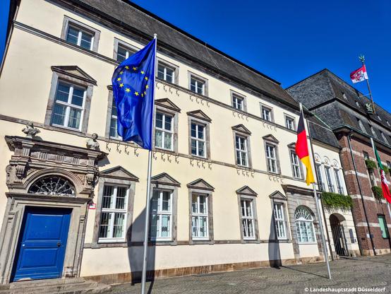 Eine blaue Europaflagge weht vor dem Rathaus in Düsseldorf im Wind.