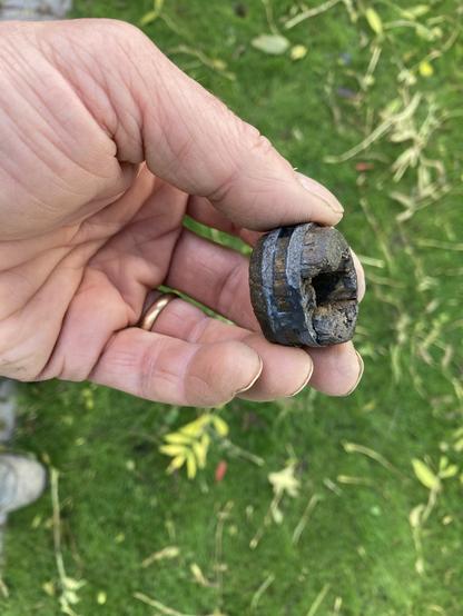Composite object of lead and waterlogged wood. A fragment of wood has detached within the finds bag. The object is a small round lead 'wheel shaped' with a central circular perforation with three slits around the edge. A roundel of waterlogged wood is secured within the wheel with two wooden facings on each side with bevelled edges. There is significant loss of wood on each side. The lead is in very good condition with no observed carbonate compounds or disfigurement. Slight incomplete gap in lead roundel suggests the lead has been cast on to the wood. The ends have been worked with the original surface at each end being carved from a radially faced billet of heartwood. Faint marking out line around circumference of each original wooden end.