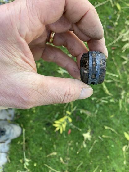 Composite object of lead and waterlogged wood. A fragment of wood has detached within the finds bag. The object is a small round lead 'wheel shaped' with a central circular perforation with three slits around the edge. A roundel of waterlogged wood is secured within the wheel with two wooden facings on each side with bevelled edges. There is significant loss of wood on each side. The lead is in very good condition with no observed carbonate compounds or disfigurement. Slight incomplete gap in lead roundel suggests the lead has been cast on to the wood. The ends have been worked with the original surface at each end being carved from a radially faced billet of heartwood. Faint marking out line around circumference of each original wooden end.