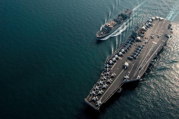 USS Harry S Truman seen from above with, presumably temporarily, a full deck park of aircraft. A replenishment vessel is aside, presumably ready to drop a buoy in the vicinity of the next victim.