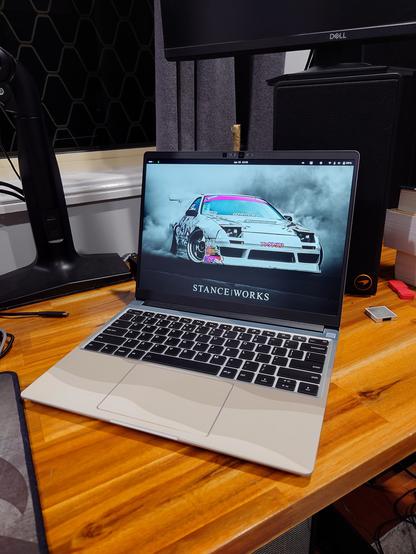 The same Framework laptop from a different angle showing off the display and keyboard, which has a super key instead of a Windows key. The GNOME desktop is visible with a 180SX drift car for the background.