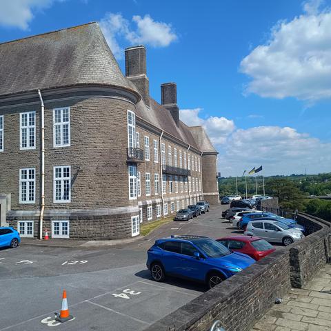 A picture of Carmarthen Castle. Looking. towards the car park. There appears to be a faded EU flag flying on the flagpole.