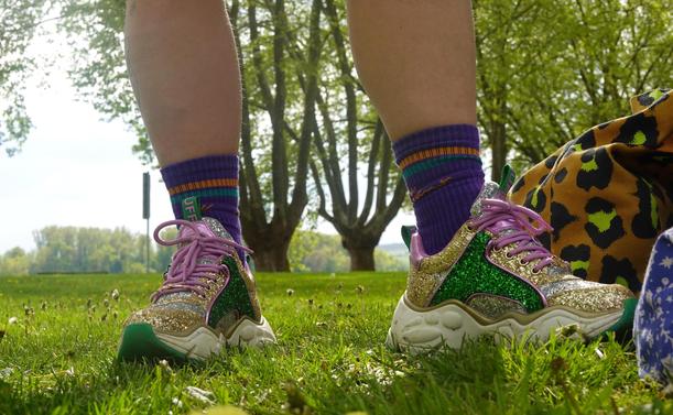 Someone wears very glittery shoes. Standing on a meadow. Close-up detail
