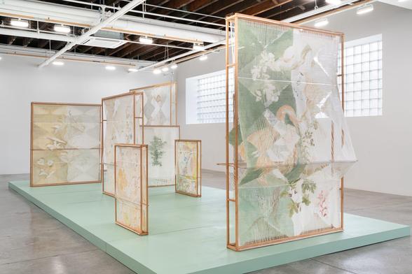 an installation of numerous woven, freestanding textile sculptures inside of a naturally lit gallery space