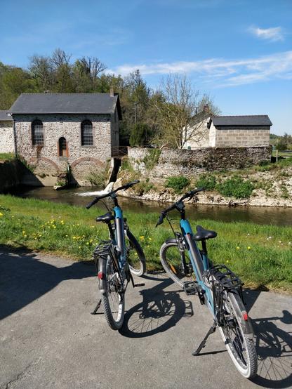 Deux vélos bleu devant un moulin à eau