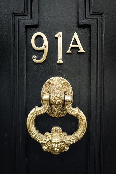 A door knocker on a black door.