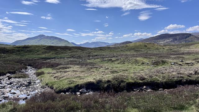 Another upland photo on a sunny day, in the foreground a small burn cuts through the heather, in the distance on the left the triangular hill Creag Dhubh (black crag), with Glenbanchor and the Monadhliath Mountains to the right.
