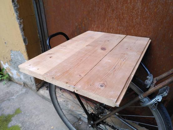 Three planks have been joined to form a board that is resting on a bicycle rack.