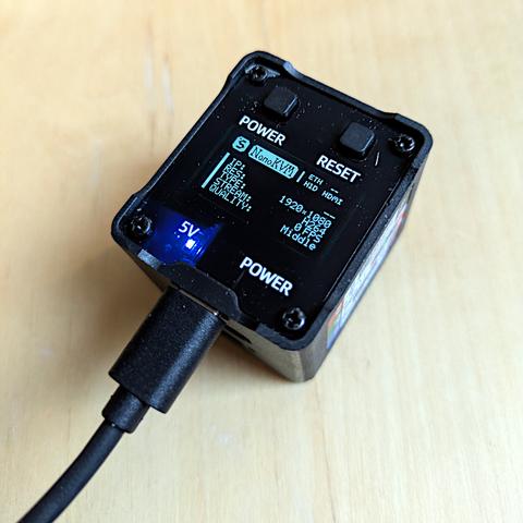 A small cube with a display showing (no) IP address and some other information, powered by a USB cable