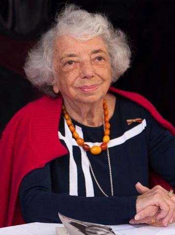 Margot Friedländer 
Das Bild zeigt eine grauhaarige Frau mit schwarzweißem Oberteil und roter Jacke