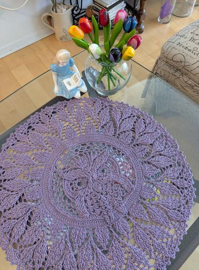 Alice, a little girl royal doulton figurine, wearing a blue dress is reading a story to an owl ( purple crochet doily of an owl ). Alice is sitting under a clear vase full of vividly painted wooden tulips.