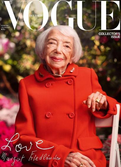 Cover der Zeitschrift "Vogue" mit Margot Friedländer auf dem Titel. Sie sitzt in einem noblen leuchtendroten Zweireiher mit einer Brosche am Kragen in einem Gartenstuhl und hat einen Arm auf die Lehne gestützt. Der Garten hinter und neben ihr ist unscharf im Bild. Oben steht in weißen Großbuchstaben über die Breite der Seite hinweg VOGUE. Unten links in weißer Handschrift "Love, Margot Friedländer".