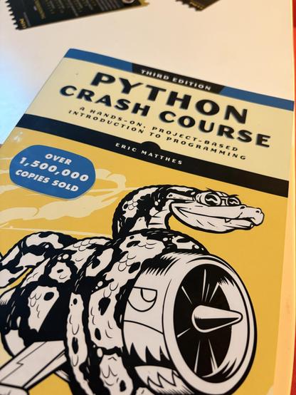 The image features the cover of the book "Python Crash Course" by Eric Matthes, which is identified as the third edition. The cover includes a stylized illustration of a snake and highlights that over 1,500,000 copies have been sold