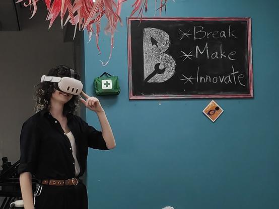 Poppy wearing her headset and smiling in front of the Break Make Innovate sign at Birkenhack