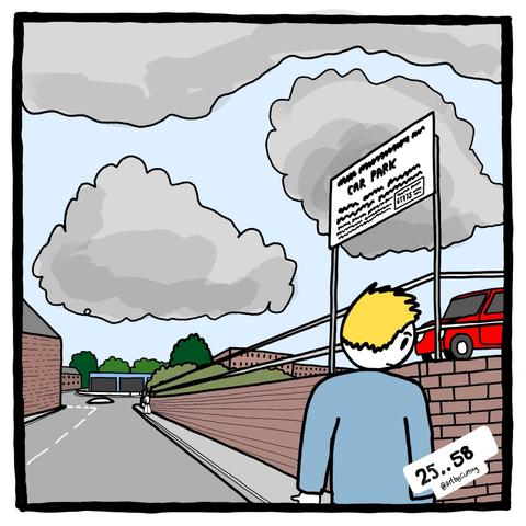 Pictured walking alongside brick wall below a carpark. Lots of distant buildings under a blue grey sky