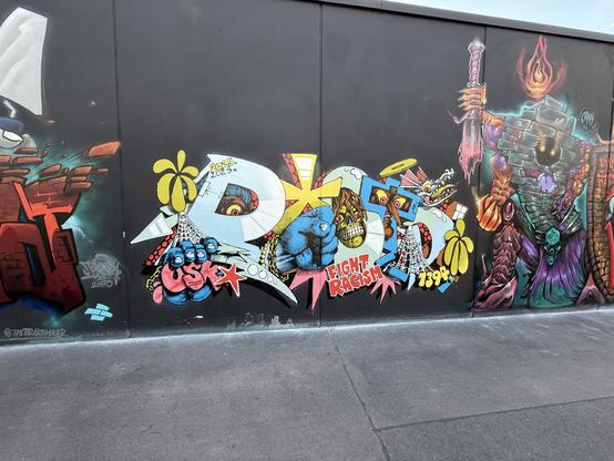 Graffiti of yellow/whote/blue letters saying "Roto",behind the letters are undead creatures, and the phrase "fight racism" is at the bottom.