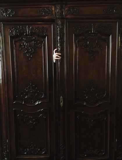 Depiction of a female hand with long nails emerging from a Victorian closet.
Original photo by Nona Limmen
