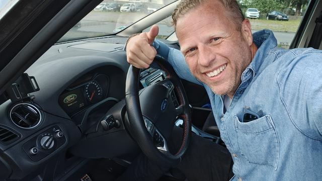 Ik in de auto, hangend op het stuur.