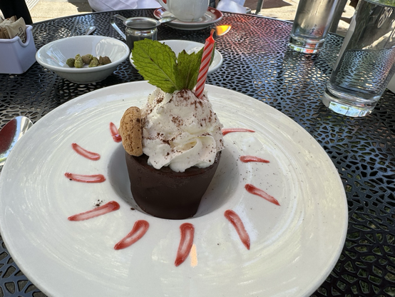 Chocolate dessert with almond cookie whipped cream mint leaves and birthday candle