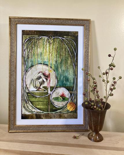 Product photo of a framed illustrated print inspired by The Frog Prince, propped up against a butter yellow wall on a wooden plank. A nearby vase of berries compliments the piece.