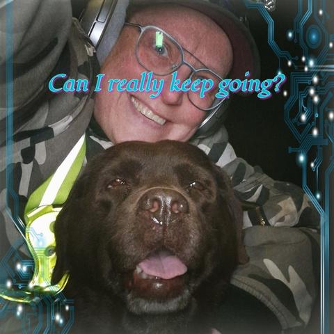 A close-up selfie of a smiling person wearing glasses, a camouflage hoodie, headphones, and a cap, embracing a happy chocolate Labrador Retriever. The person’s reflective safety strap glows slightly, and the dog’s face is front and center with its tongue out and eyes gently squinting, exuding warmth and contentment. Overlaying the image in stylized, gradient blue-to-pink text is the question: “Can I really keep going?” The edges of the image are framed with digital circuit patterns, giving the picture a tech-futuristic aesthetic. The juxtaposition of emotional vulnerability in the text and the genuine joy in the selfie creates a poignant contrast.