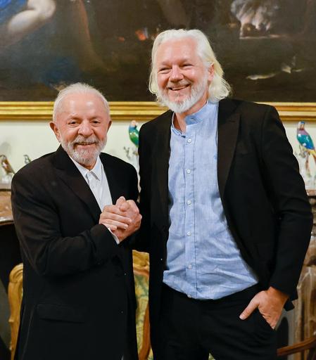 Julian Assange and Président Lula shaking bands together and smiling