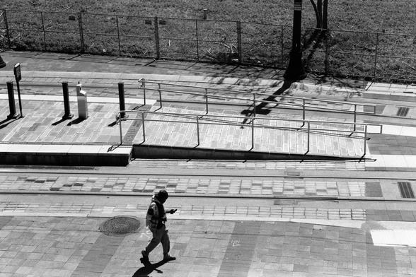 A view of a person walking across a light rail platform, taken from above