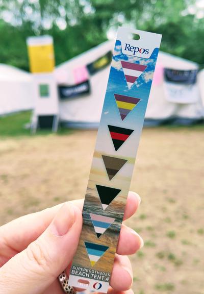Picture of fingers holding a blank plate with coloured triangles on a beach background
