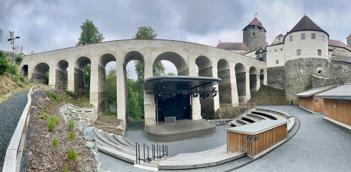 Zugangsbrücken mit 11 Torbögen und einer Freilichtbühne unten und der Burg rechts