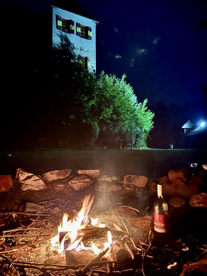 Lagerfeuer bei Nacht mit Blick auf die beleuchtete Ritterburg