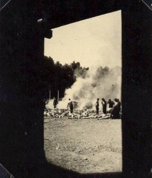 Group of prisoners of Auschwitz burning corpses of people murdered in gas chambers in burning pits. Smoke is visible above the pile.