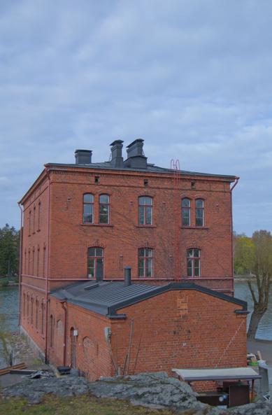 A 3-story high red brick building by the bay.