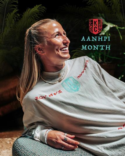 Close of up Mace wearing our AANHPI long-sleeved shirt and text on the photo that says, "AANHPI Month"