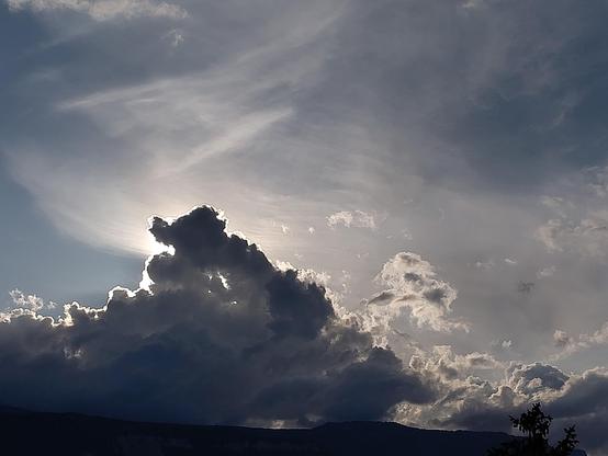 Ciel clair de coucher de soleil, avec juste un gros nuage assez sombre juste devant le soleil, qui lui fait des bords lumineux